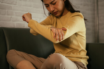 Young Asian discomfort woman holding hand and pressing points of elbow while suffering from elbow...