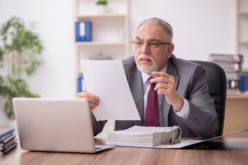 Naklejka premium Old male employee working in the office