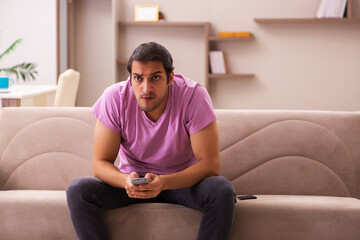 Obraz premium Young man watching tv at home during pandemic