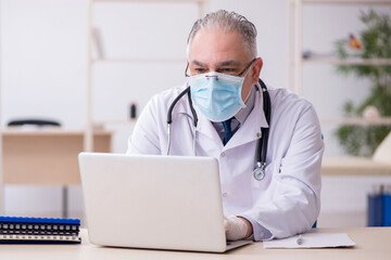 Old male doctor working in the clinic