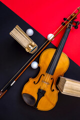 Violin, bow and books on a red-black background, top view