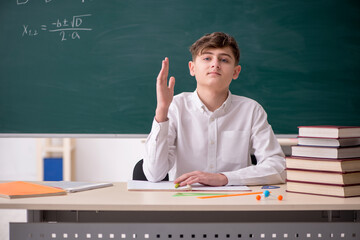 Schoolboy studying math in front of blackboard