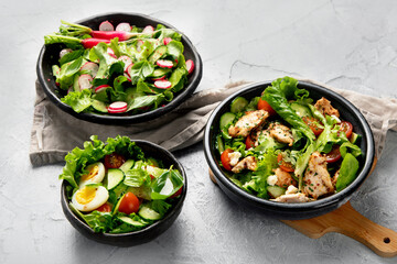 Freshly made salads on light gray background. Seasonal food concept.
