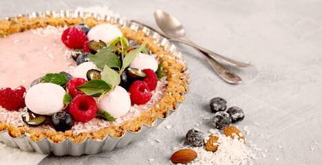 Strawberry vanila tart topped with berries on light gray background.
