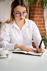 Boss business woman working makes notes notepad sitting cafe drinking coffee. Freelancer copywriter glasses write notes. office worker coffee break cafe.
