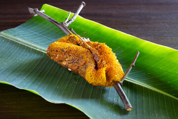 Honeycomb from the nature stick on tree branch is clipped put on green banana leaf and brown wooden...