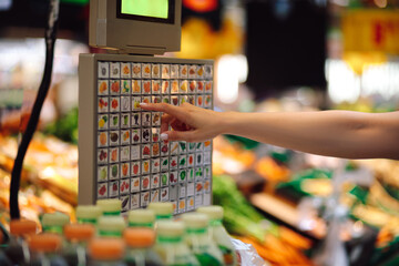 Woman's hand selects desired position on display of electronic scales in vegetable department of...