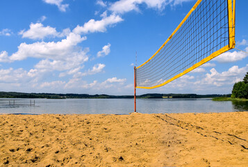 Beach volleyball court situated next to the lake and forest on a sunny day