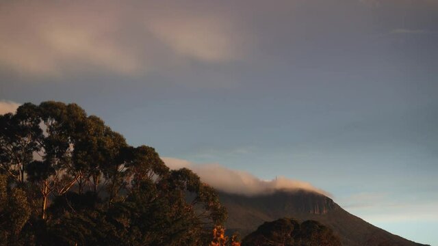 timelapse of dusk and sunset with clouds over the mountains with eucalyptus gum trees in the foreground shot in Tasmania, Australia