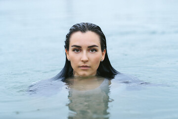 A dark-haired girl swims in the lake and takes a photo session