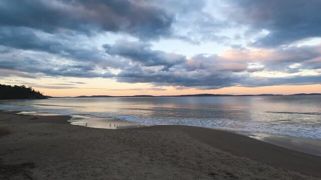 sunset on pristine beach in Southern Tasmania in Australia with colorful clouds reflecting over the Pacific Ocean and no people