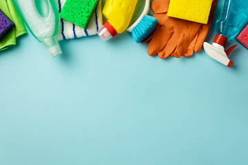 Set of various cleaning supplies on blue background with copy space, top view