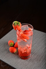 iced strawberry fruit cooler mocktail / kombucha in glass on bar counter dark night background cold halal drink menu