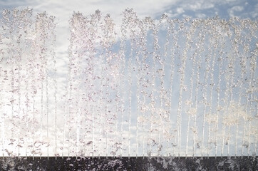 Wall of drops and trickles of water from the fountain rising up
