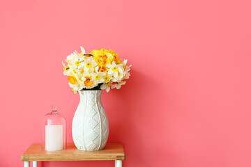 Vase with narcissus flowers on table in room