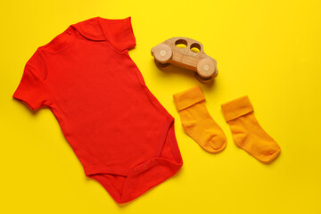 Baby clothes, socks and toy on color background