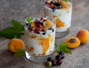 Two glasses of yogurt with apricots, strawberries and black currants