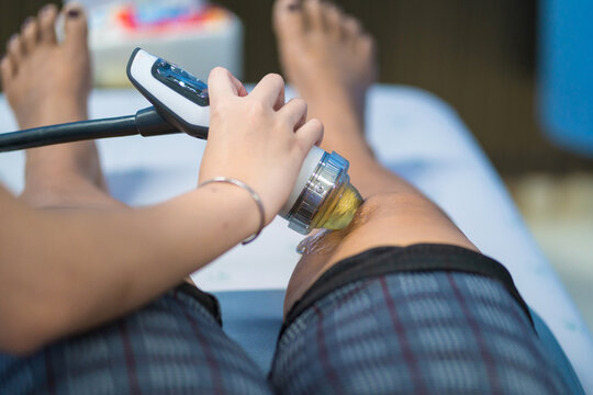Therapist Doctor is doing shock wave therapy on Knee woman in hospital, Patient is getting Profilaxing Procedure of Physiotherapist. Health, Medicine
