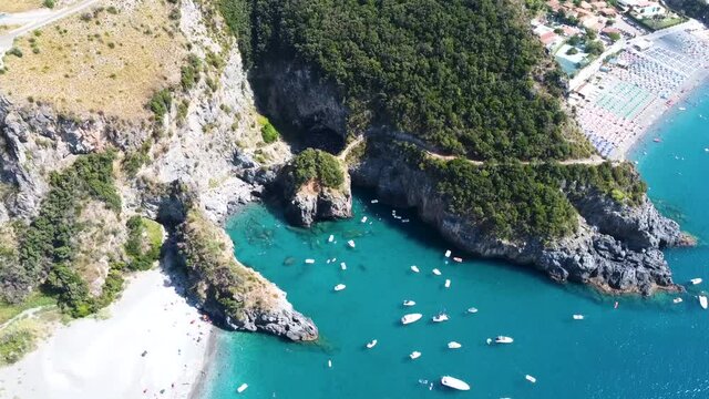 An Italian summer around Arcomagno, San Nicola Arcella on a sunny day and turquoise water filled with boats.