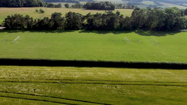 Flying alongside a green village football pitch in Kent, UK