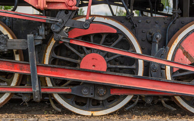 The flywheel of an old locomotive standing on the tracks.