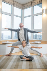 Dad and his kids doing yoga together at home and looking involved