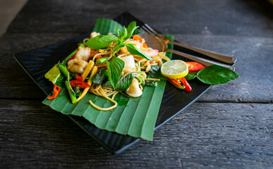 A portion of seafood spaghetti with Thai herb on the black dish photo taken from the top view. The hot and spicy taste food.
