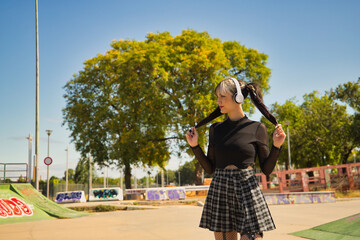 Young and beautiful girl with heterochromia and punk style with white headphones holding her...