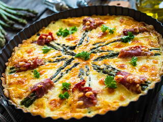 Tart with asparagus and serrano ham on wooden table
