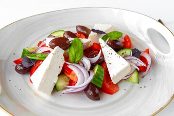 Greek salad in plate on white wooden background