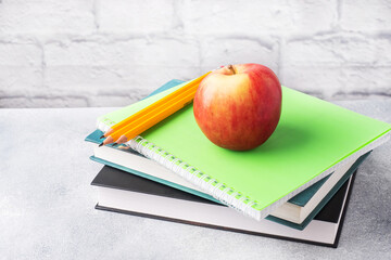 A fresh red apple on a stack of books and notebooks. The concept of a school breakfast snack. Copy space,