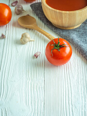 Focus tomato, Delicious tomato soup in wooden bowl on white wood table, Copy space for word. Healthy food in morning concept. Verticle picture.