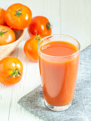 Fresh tomato juice in glass and tomatos on white wooden table, Copy space for word. Healthy drink in morning concept. verticle picture.