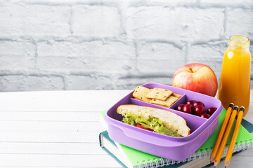 Delicious healthy sandwich in a lunch box, cookies and cherries. Take lunch with you to school or the office. Juice in a bottle and an apple.
