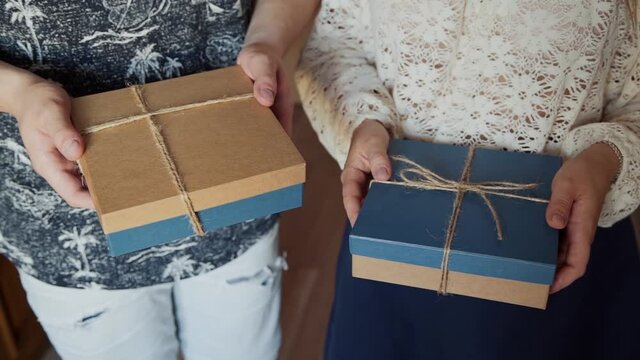 Gift craft ecological boxes tied with twine are hold by a caucasian man and woman, close-up.