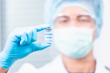 Young doctor or scientist in uniform wearing a face mask showing up coronavirus vaccine, nurse man holding bottle COVID-19 vaccination at laboratory, Healthcare And Medical concept