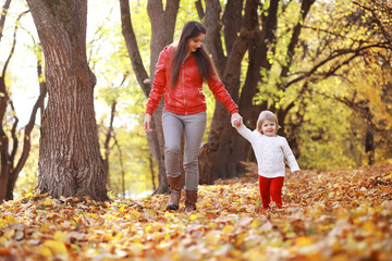 Young family on a walk in the autumn park on a sunny day. Happiness to be together.