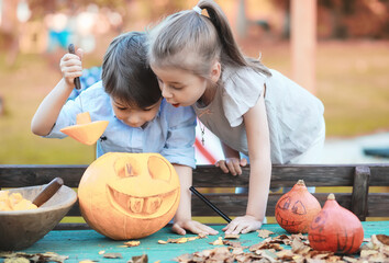 Fototapeta premium Autumn traditions and preparations for the holiday Halloween. A house in nature, a lamp made of pumpkins is cutting out at the table.