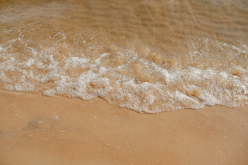 Sand on the beach with champagne color. Close up top view. Clean sea shore. A natural backdrop of water and sand