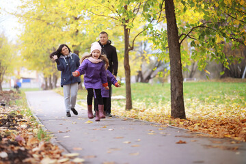 Young family on a walk in the autumn park on a sunny day. Happiness to be together.