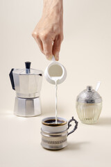 Pouring milk in  cup of coffee, geyser coffee maker and shugar