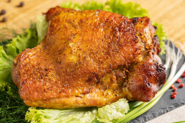 Whole roasted turkey thigh. Top view. Close-up turkey dish garnished with herbs. Stone serving board, wooden background.