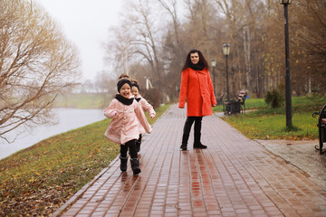 Young family on a walk in the autumn park on a sunny day. Happiness to be together.