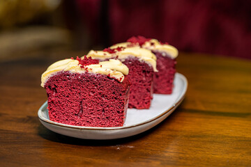 A sliced red velvet cake in a plate on a wooden table