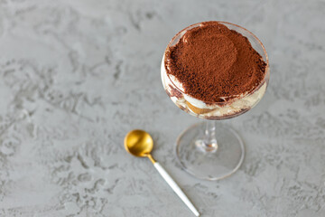 Tiramisu dessert in a glass on gray surface