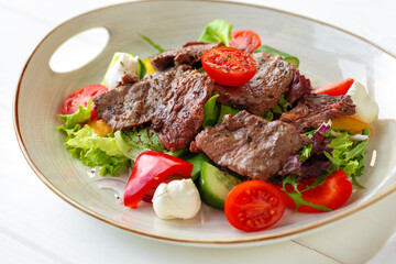Fillet of beef with vegetable salad on wooden table
