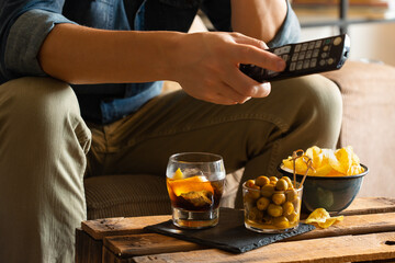 Man drinking vermouth and eating snacks after work at home