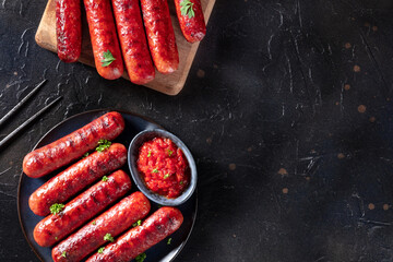 Sausages with ketchup, shot from the top on a black background with a place for text. Beef and pork...