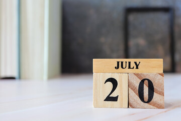 Cube wooden calendar showing date on 20 July. Wooden calendar with date on the table. blur objects on background