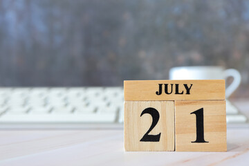 Cube wooden calendar showing date on 21 July. Wooden calendar with date on the table. blur objects on background